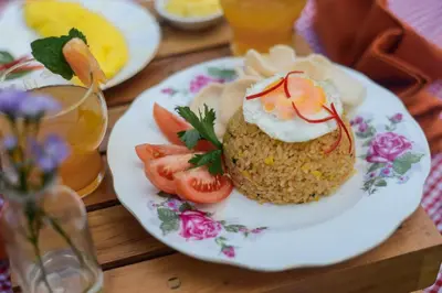 a plate of food with sushi and tomatoes on a table at RakaAyu Kuta in Kuta