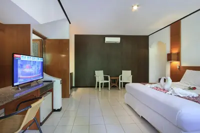 a bedroom with a bed and a tv in a room at Puri Naga Beachfront Cottages in Legian