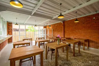 a restaurant with wooden tables and a brick wall at Moson Villa Legian in Legian
