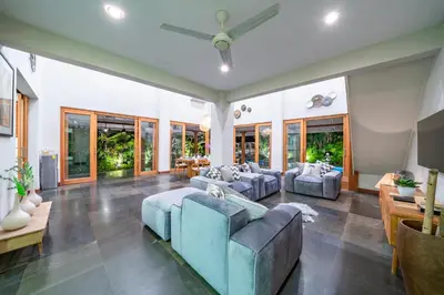 a living room with couches and tables and windows at Villa Litera Canggu Bali in Canggu