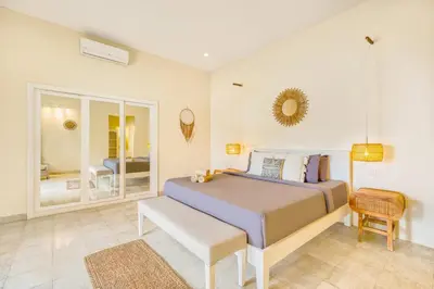 a bedroom with a bed and a chair and a mirror at Villa Milano - Private 6 BDR Villa in Seminyak, prime Location, Pool & Garden in Canggu