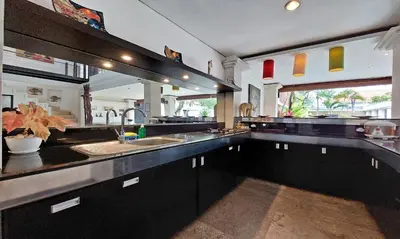 a large kitchen with black cabinets and a sink at Harmony Villa Dua in Seminyak