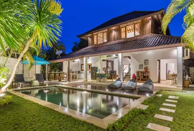 a villa with a swimming pool in front of a house at Villa Bunga 1 in Seminyak