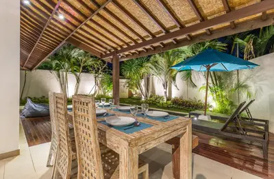 an outdoor dining room with a table and a blue umbrella at Villa Bunga 1 in Seminyak