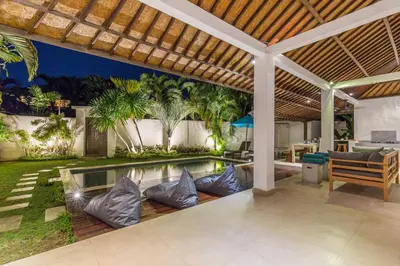 an outdoor patio with a swimming pool and a house at Villa Bunga 1 in Seminyak