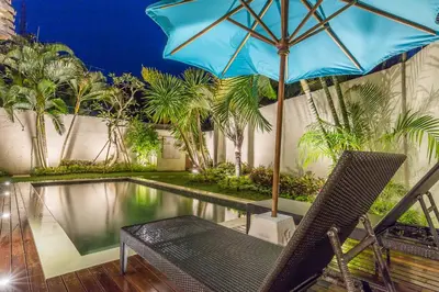 a chair and an umbrella next to a swimming pool at Villa Bunga 1 in Seminyak