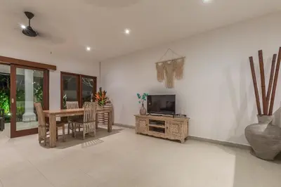 a living room with a table and a television and a table and chairs at Bunga 2 in Seminyak