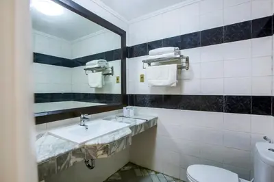 a bathroom with a sink and a mirror and a toilet at Bali Bungalo Hotel in Kuta