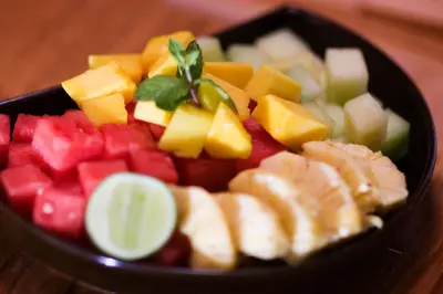 a black bowl filled with different types of fruit at Bali Bungalo Hotel in Kuta
