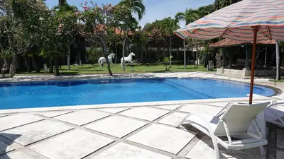 a swimming pool with a chair and an umbrella at Bali Bungalo Hotel in Kuta