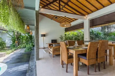 an outdoor dining room with a wooden table and chairs at Pulesari 3 bedrooms in Seminyak
