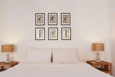 a bedroom with a white bed with three pictures on the wall at Pulesari 2 bedrooms in Seminyak