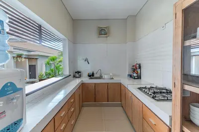 a white kitchen with a stove and a sink at Svarna Suites Seminyak in Seminyak