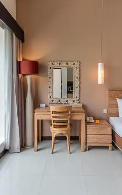 a bedroom with a desk with a mirror and a bed at Svarna Suites Seminyak in Seminyak