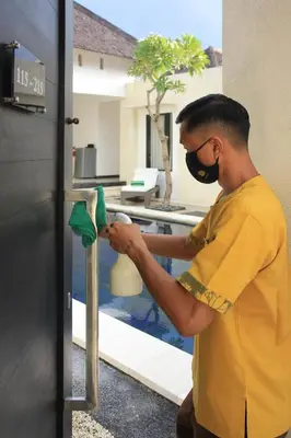 a man wearing a mask cleaning a door at The Haere Seminyak - By Astadala in Seminyak