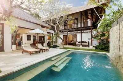a house with a swimming pool in front of a house at Jimbaran Beach Villas by Nakula in Jimbaran