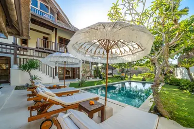 an outdoor patio with umbrellas and a swimming pool at Jimbaran Beach Villas by Nakula in Jimbaran