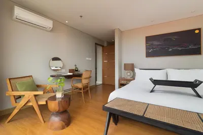 a bedroom with a bed and a table and a desk at Beachwalk Residence in Kuta