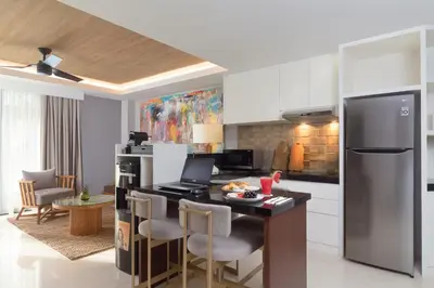 a kitchen with a kitchen island with chairs and a refrigerator at Beachwalk Residence in Kuta