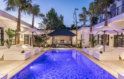 a swimming pool with chairs and umbrellas next to a building at Villa Lora in Seminyak
