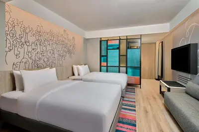 a hotel room with two beds and a tv at Aloft Bali Kuta at Beachwalk in Kuta