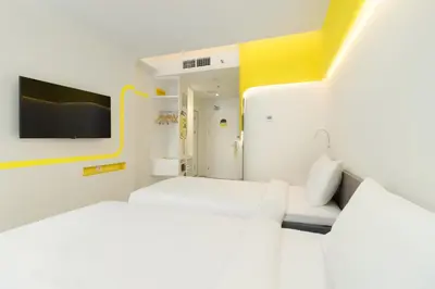 a white room with a bed and a tv at YELLO Hotel Kuta Beachwalk Bali in Kuta