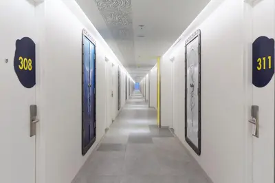a corridor with white walls and a long hallway with doors at YELLO Hotel Kuta Beachwalk Bali in Kuta