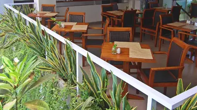 a restaurant with wooden tables and chairs and plants at The Legian Sunset Residence in Seminyak