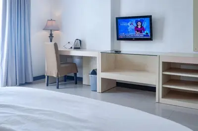 a hotel room with a desk and a tv on a wall at KoolKost at Bypass Jimbaran - Minimum Stay 30 Nights in Kuta