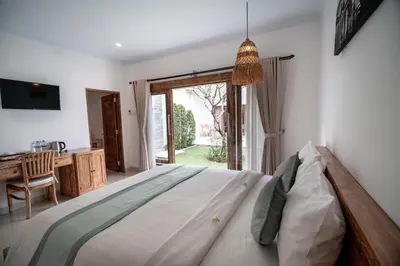 a bedroom with a bed and a desk and a window at The Eight Villa & Rooms Bali - Seminyak in Seminyak