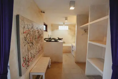 a bathroom with a painting on the wall and a bench at Villa Dewi in Seminyak