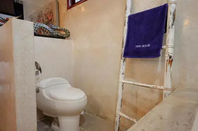 a bathroom with a toilet and a blue towel at Villa Dewi in Seminyak