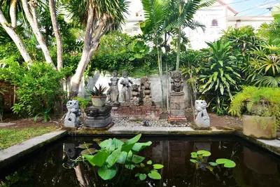 a garden with a pond with statues in it at Bebek Cottages Sanur in Sanur