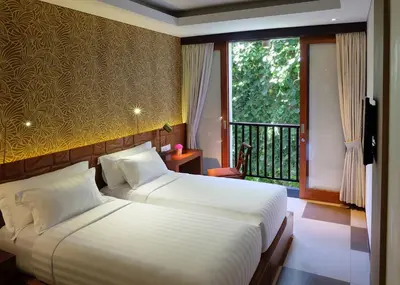 two beds in a hotel room with a balcony at Sun Island Hotel & Spa Legian in Legian