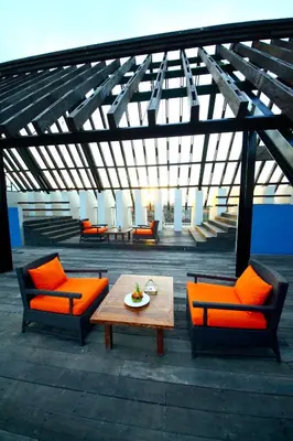 a patio with orange chairs and a wooden table at Sun Island Hotel & Spa Legian in Legian