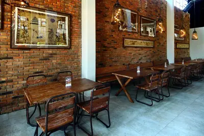 a restaurant with wooden tables and chairs and a brick wall at Sun Island Hotel & Spa Legian in Legian