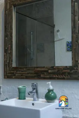 a bathroom sink with a mirror and a green vase on it at Villa di Sawah - by Unicorn Villas Bali in Kerobokan