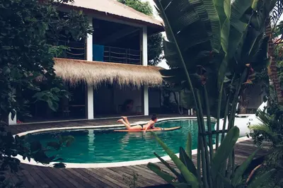 a woman laying on a surfboard in a swimming pool at Endless Summer Surf Camp Kuta in Kuta