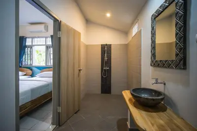 a bathroom with a sink and a bedroom with a bed at Endless Summer Surf Camp Kuta in Kuta