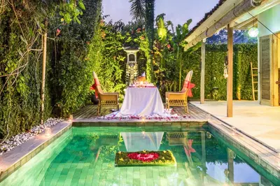 a table with a cake on it sitting next to a pool at Villa 007 in Seminyak