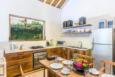 a kitchen with a table and a refrigerator at Villa 007 in Seminyak
