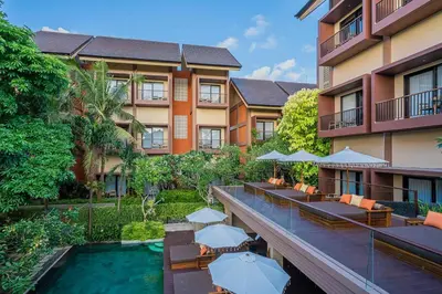 a hotel with a swimming pool and tables and umbrellas at Pandawa All Suites Hotel in Seminyak