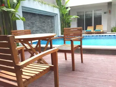 a wooden table and two chairs next to a pool at Mi Casa Residence in Seminyak