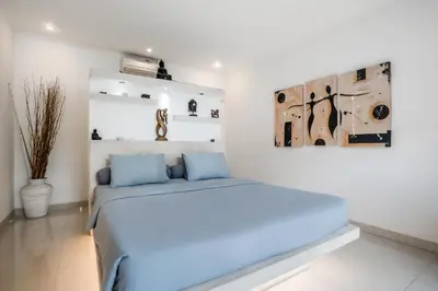 a bedroom with a blue bed and a painting on the wall at Villa Baik Baik by BaliSuperHost in Seminyak