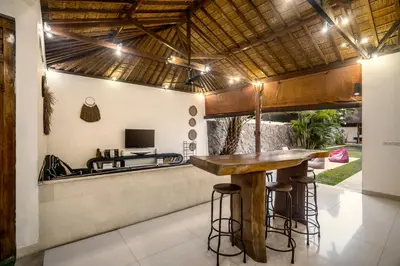 an outdoor kitchen with a wooden bar with stools at Villa Baik Baik by BaliSuperHost in Seminyak