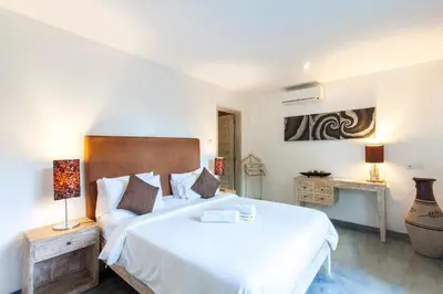 a bedroom with a large white bed and a desk at Villa Jalak in Seminyak