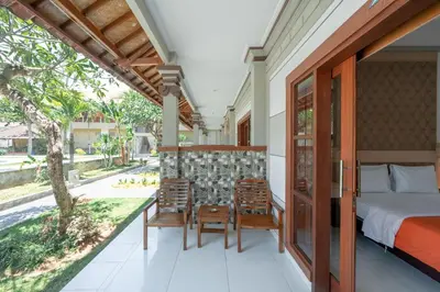 a bedroom with a bed and chairs on a balcony at Bendesa Accommodation in Kuta
