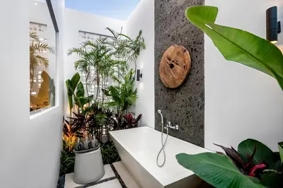 a bathroom with plants and a white bath tub at Villa Australis in Kerobokan