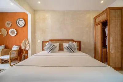 a bedroom with a large bed and a clock on the wall at White Goose Boutique Hotel in Canggu