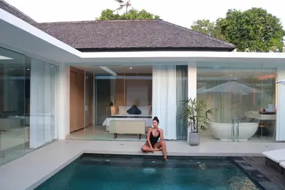 a woman sitting on the edge of a swimming pool at Alami Luxury Villa in Seminyak